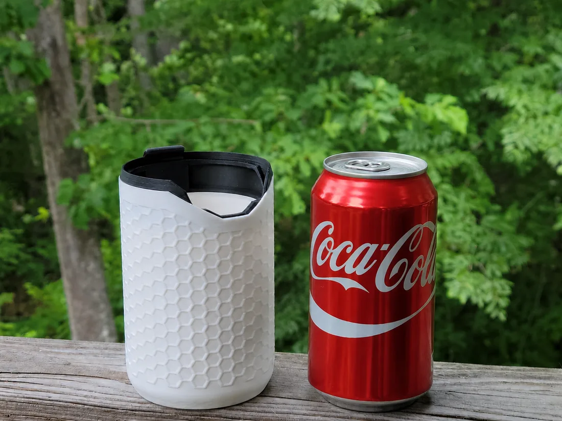 Porta-lata térmico PopTop Koozie branco ao lado de uma lata de Coca-Cola