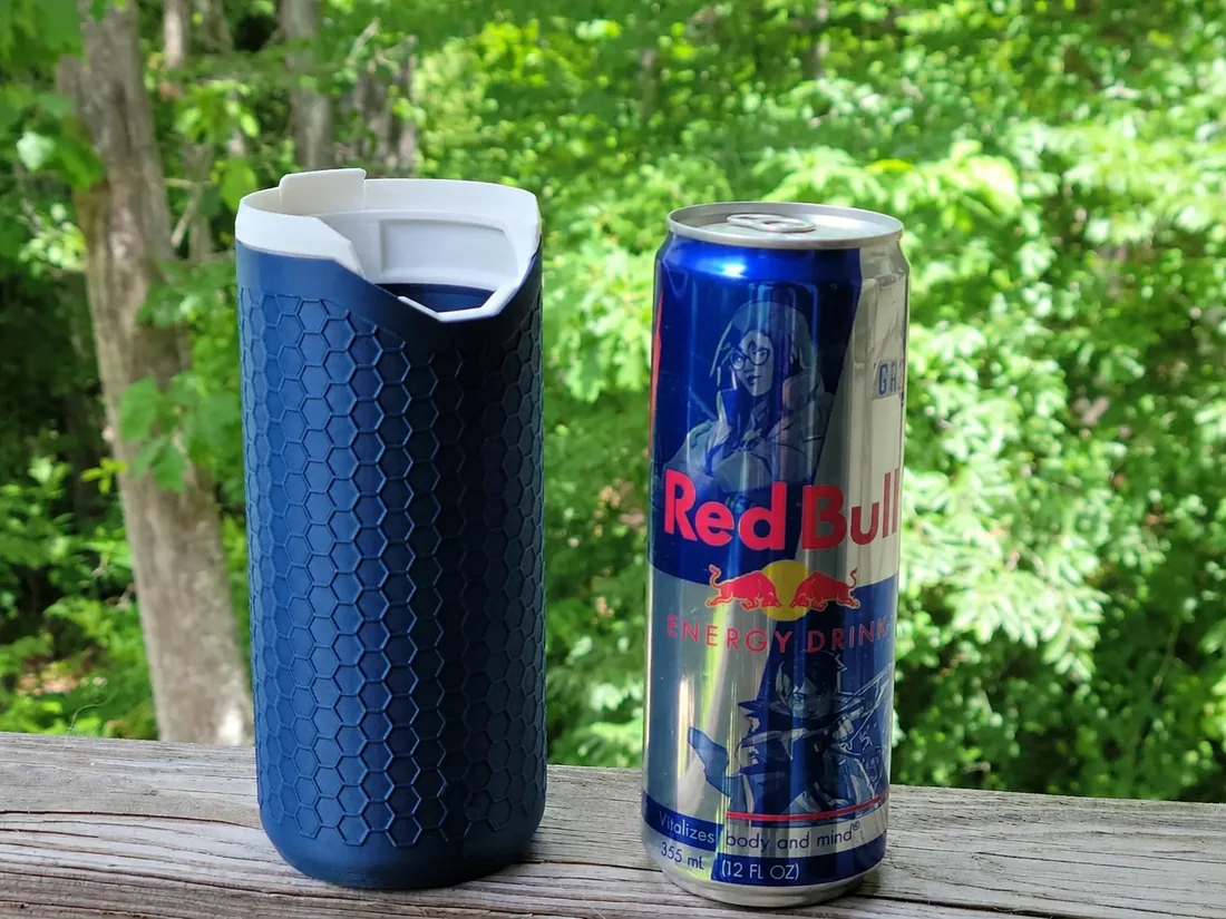 Porta-lata térmico PopTop Koozie azul ao lado de uma lata slim de Red Bull